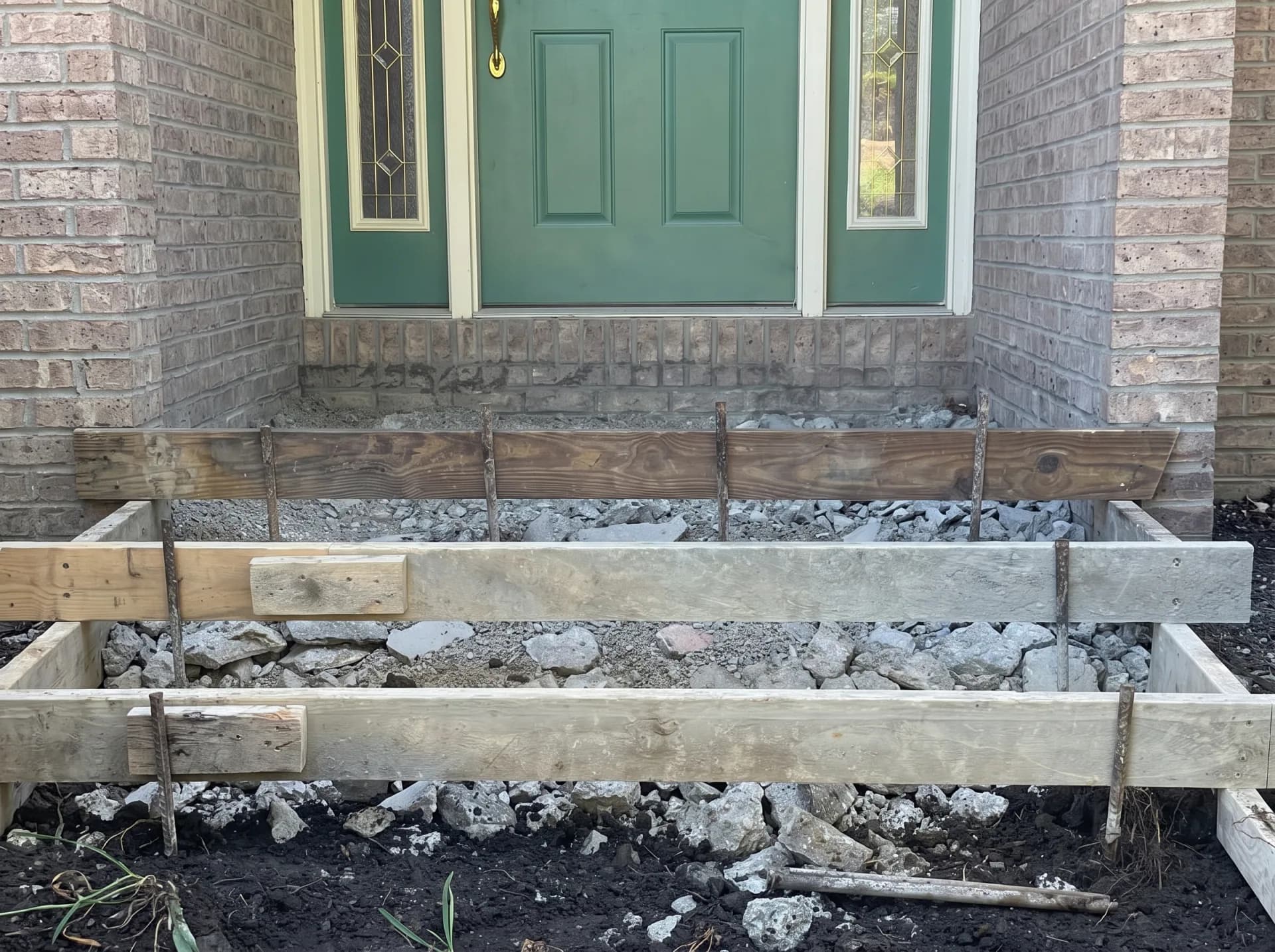 Crumbling front entryway prepped with wood forms and limestone gravel base