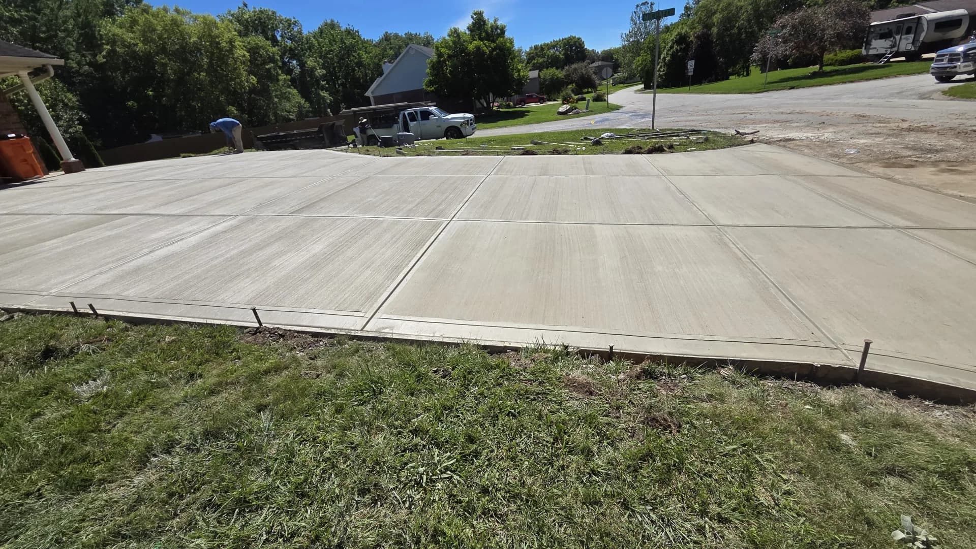 A wide shot of a newly poured, pristine concrete driveway in front of a modern Indianapolis home, showcasing clean edges and a smooth broom finish.